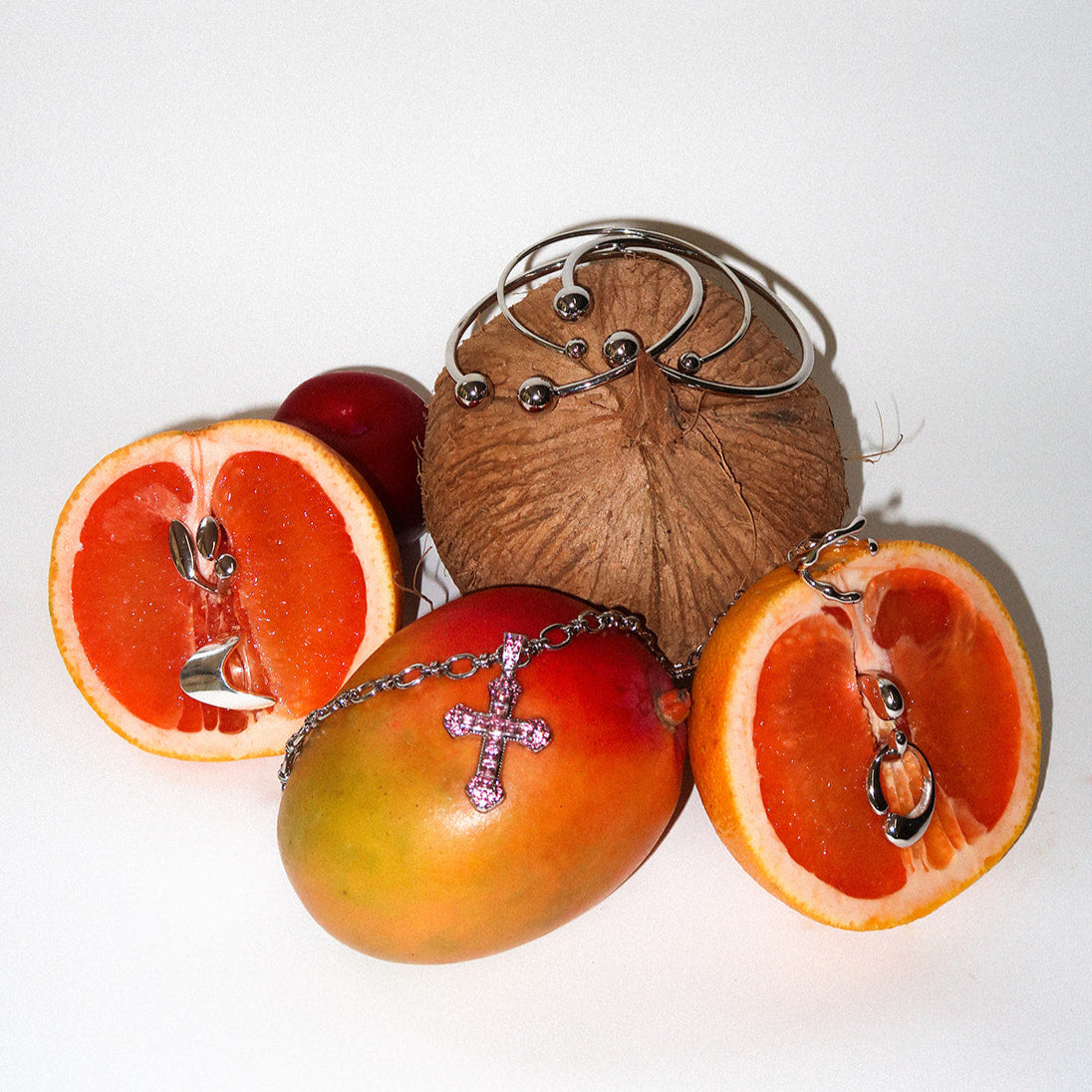 Coconut, mango, and oranges with necklaces on a white background