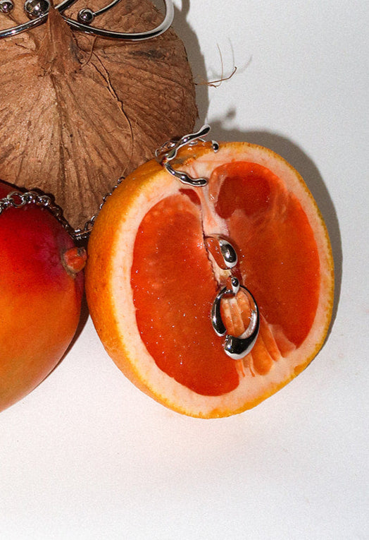 Coconut, mango, and oranges with necklaces on a white background