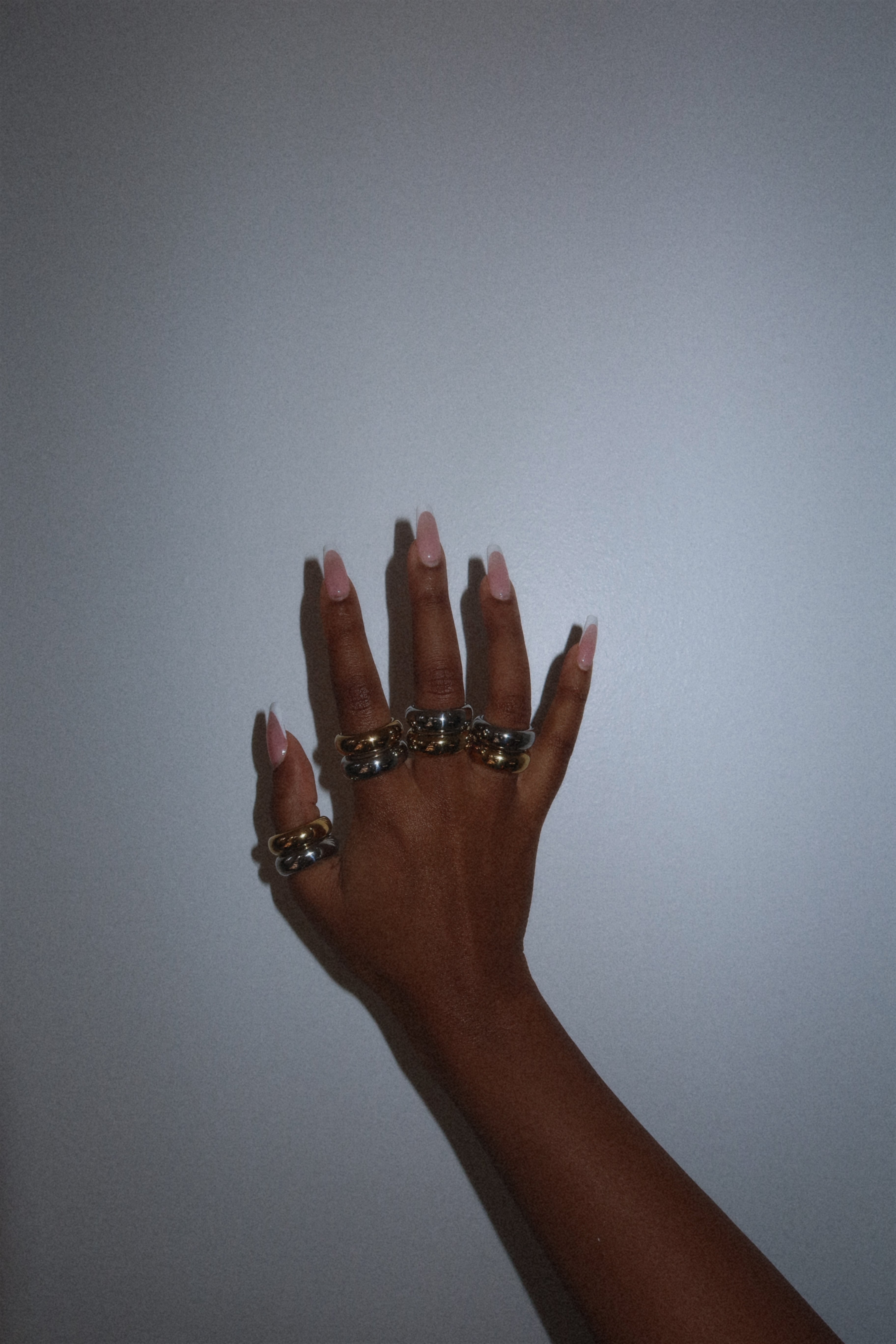 Hand with multiple rings on a plain background